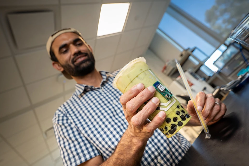 Spoluautor studie Muhammad Inam Khan, doktorand nanoinženýrství na UC San Diego Jacobs School of Engineering, předvádí umístění konečků prstů na nálepce při uchopení nápoje boba.